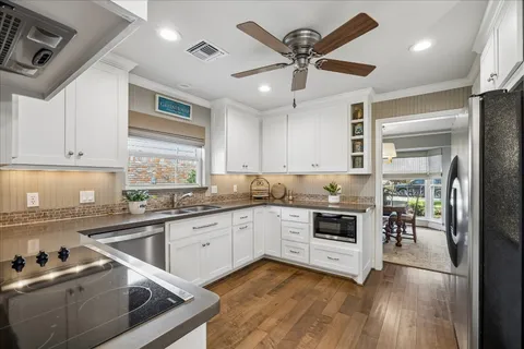 a kitchen with granite countertop stainless steel appliances a sink cabinets and wooden floor
