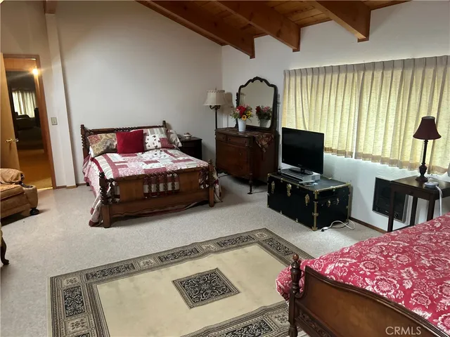 a bedroom with a bed a flat screen tv and dresser