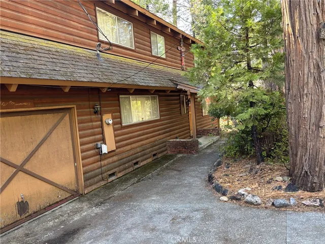 a view of a house with a yard and large tree