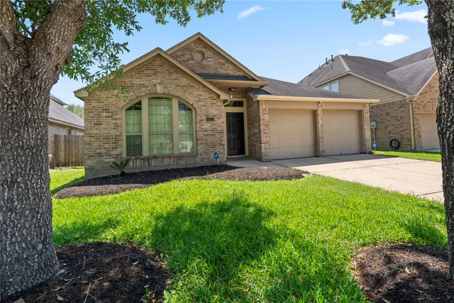 a view of a house with a small yard and a large tree