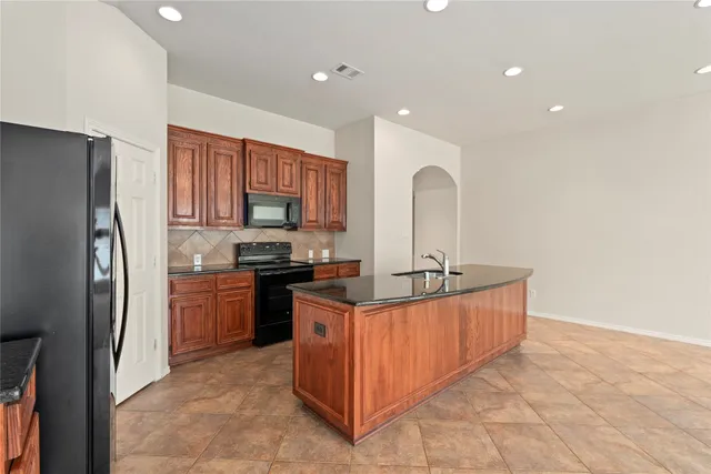 a kitchen with stainless steel appliances granite countertop a stove refrigerator and a sink