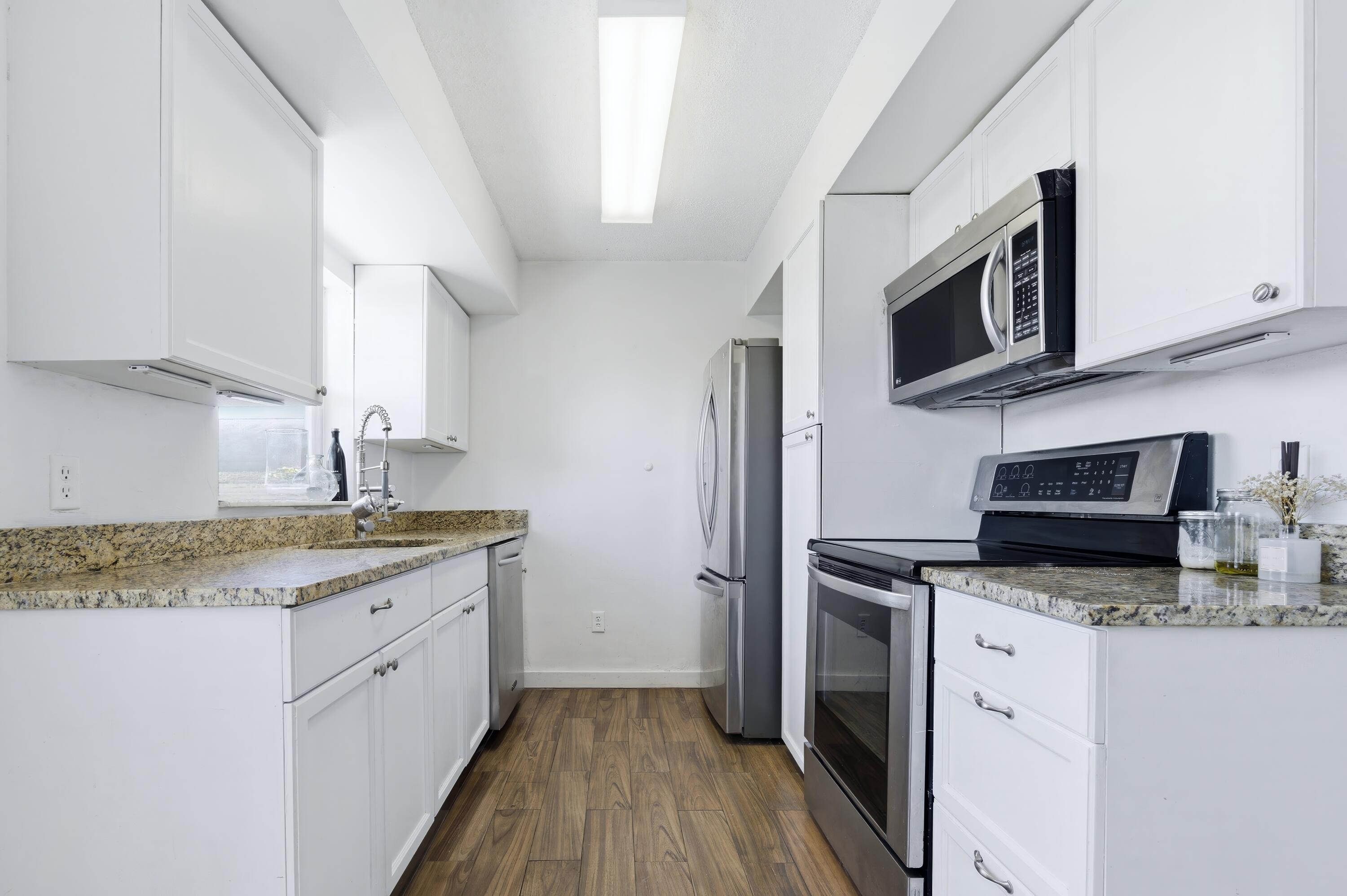 6088 Heather Street Jupiter, FL 33458 - Photo 7 of 18 a kitchen with stainless steel appliances granite countertop a sink stove and microwave