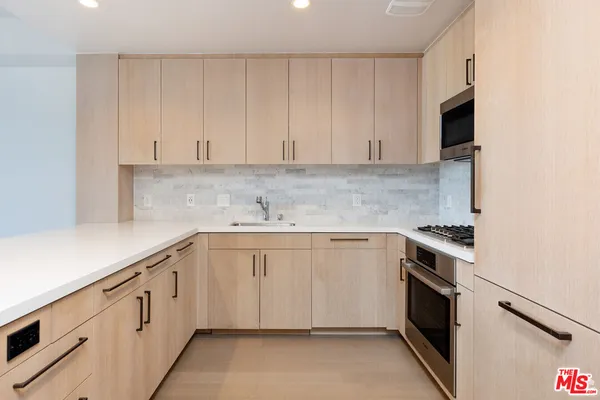 a kitchen with stainless steel appliances a dining table chairs refrigerator and sink