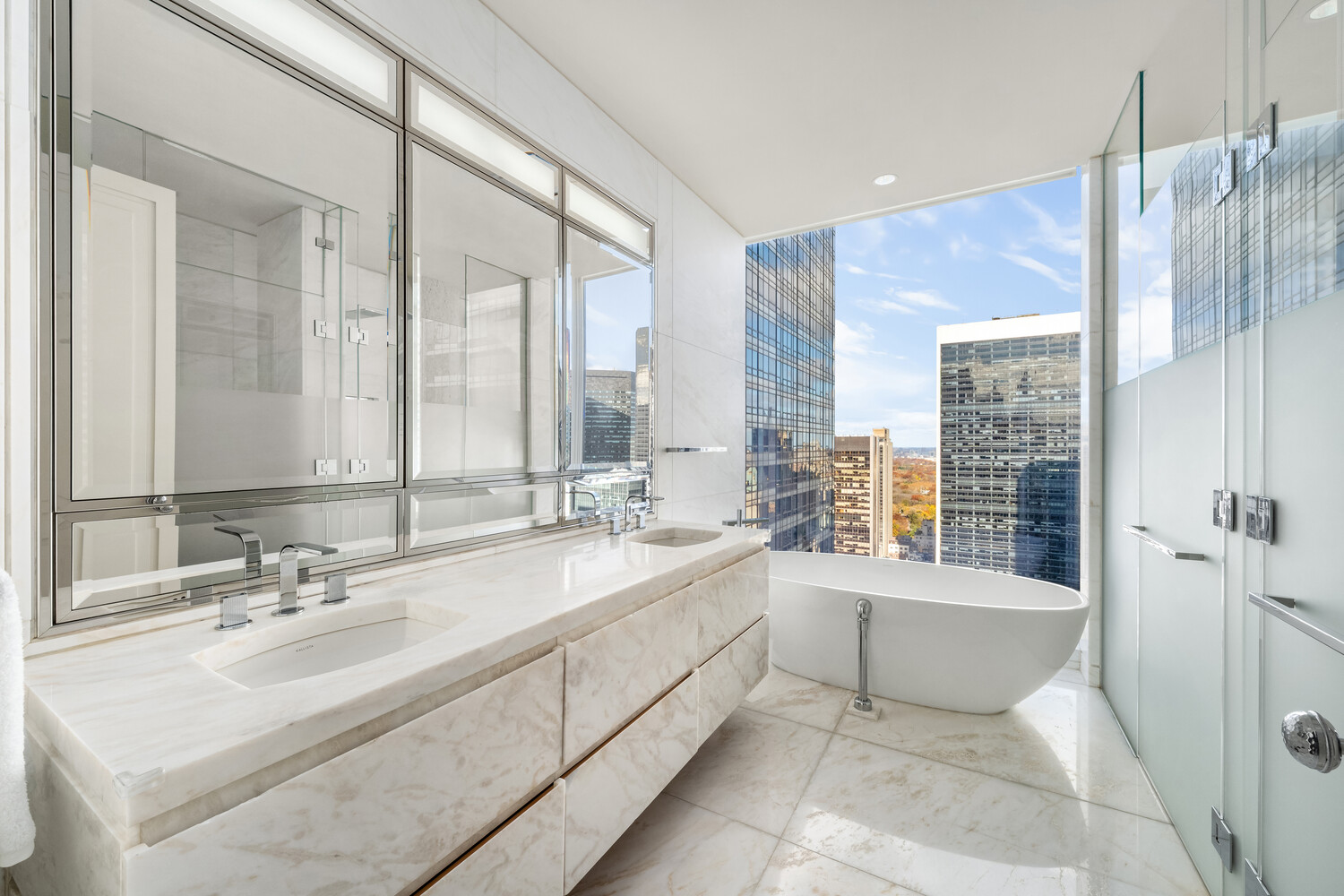20 West 53rd Street, Unit 38A Manhattan, NY 10019 - Photo 11 of 20 a large bathroom with a double vanity sink large mirror and a bathtub