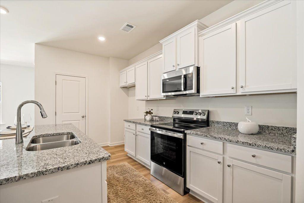 2526 Riverside Court Northeast Conyers, GA 30013 - Photo 4 of 22 a kitchen with stainless steel appliances granite countertop a sink a stove top oven and granite counter tops