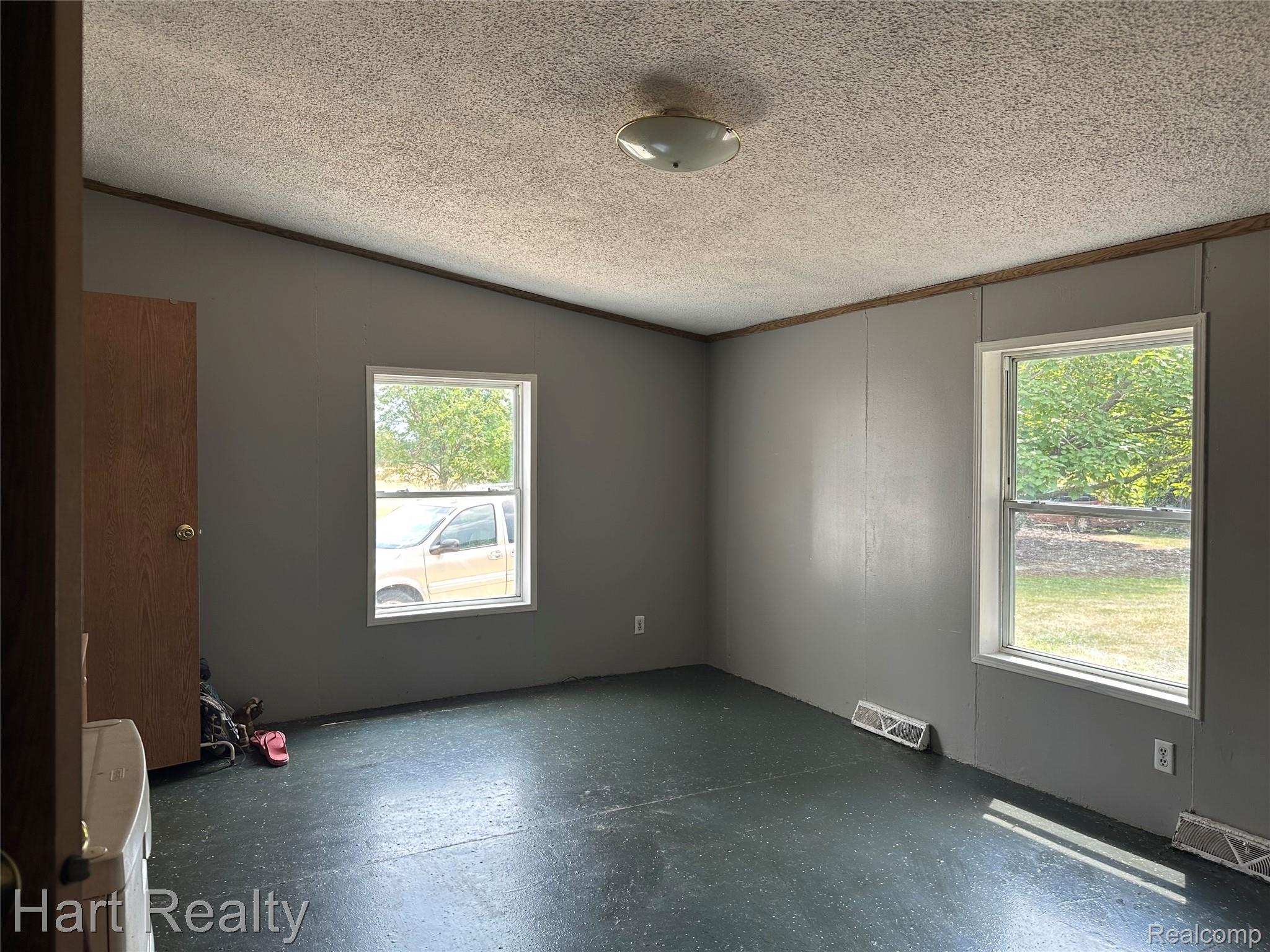 15686 Jeddo Road Brown City, MI 48416 - Photo 21 of 25 Interior room featuring two windows, gray wall paneling, a textured ceiling, and dark speckled flooring