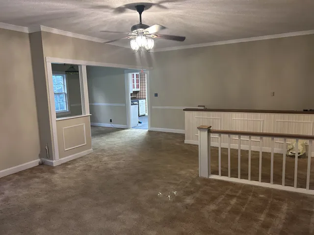 an empty room with chandelier fan and windows