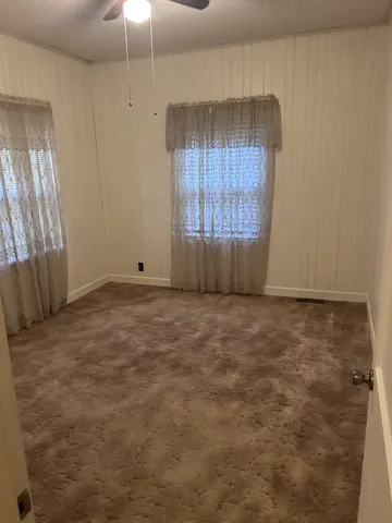 an empty room with windows and fan