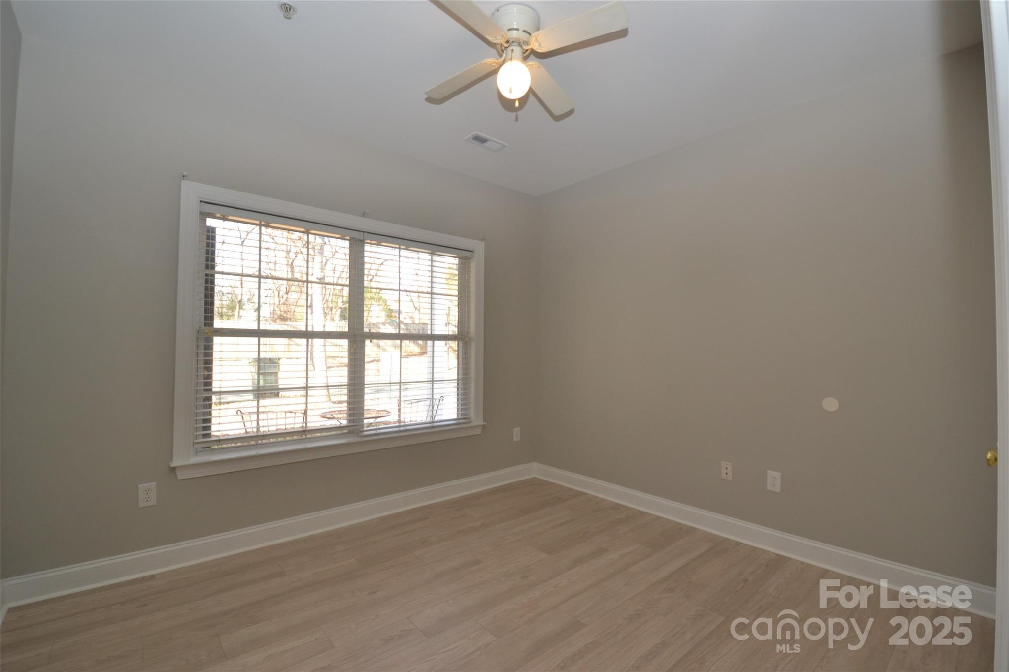 19820 Feriba Place Cornelius, NC 28031 - Photo 7 of 16 an empty room with wooden floor ceiling fan and windows