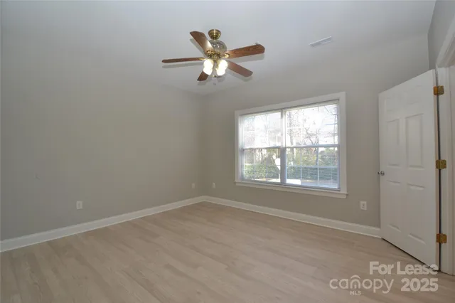 an empty room with a window and a fan