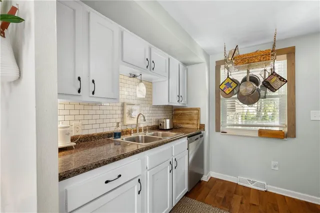 a kitchen with stainless steel appliances granite countertop white cabinets and window