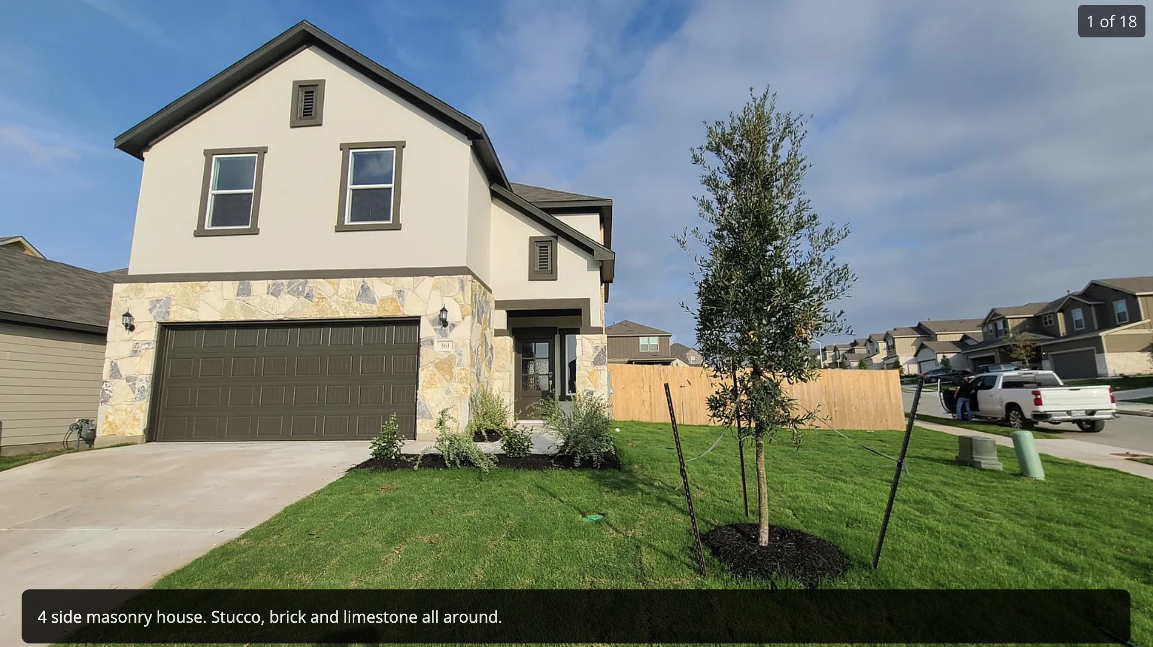 View of front of house featuring an attached garage, stone siding, concrete driveway, stucco siding, and a residential view