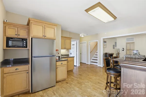 a kitchen with stainless steel appliances a refrigerator a stove a sink a dining table and chairs with wooden floor