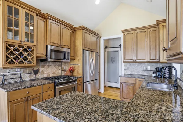 a kitchen with stainless steel appliances granite countertop a stove a sink and a microwave