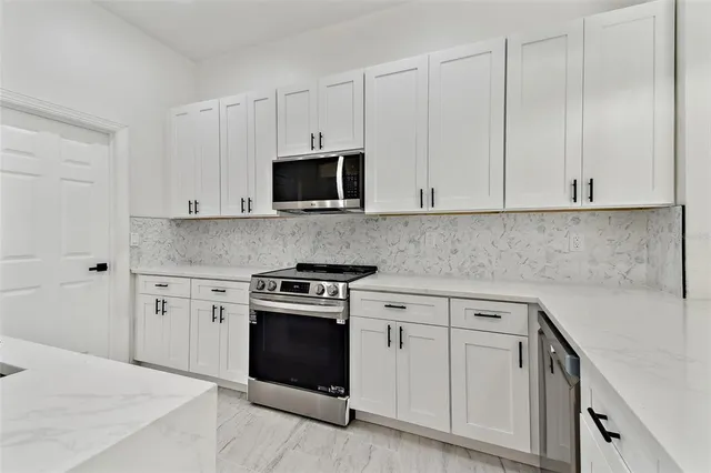 a kitchen with white cabinets and stainless steel appliances