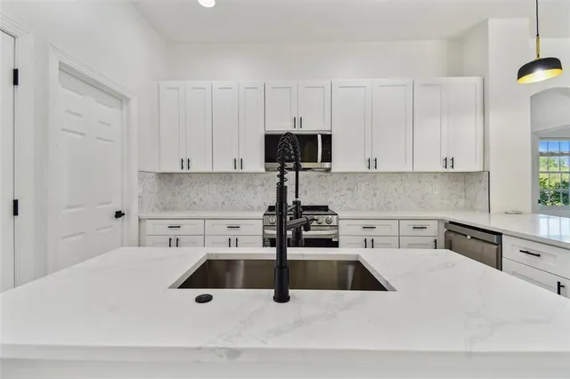 a large kitchen with white cabinets a sink a window and stainless steel appliances