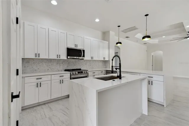 a view of a kitchen with stainless steel appliances a refrigerator and a stove top oven