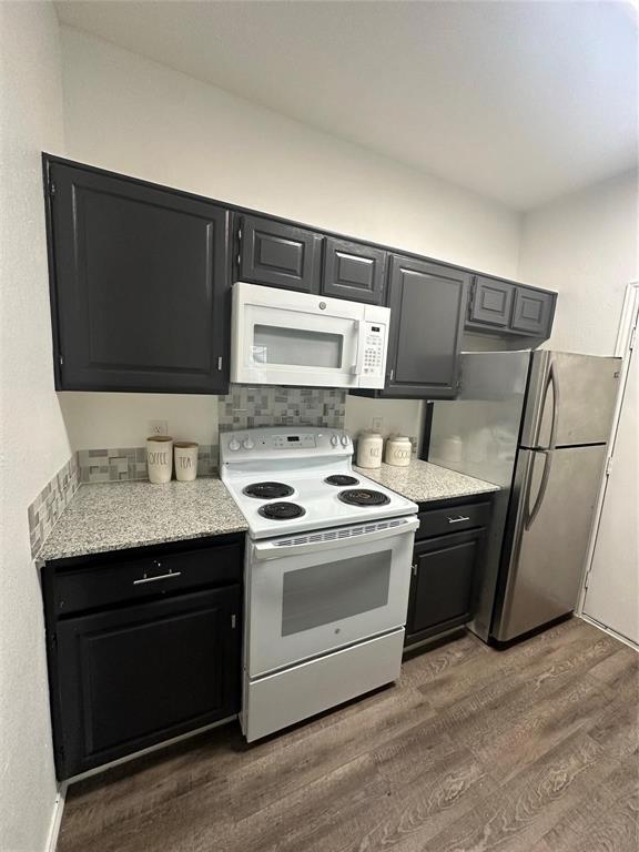 7340 Skillman Street, Unit 405 Dallas, TX 75231 - Photo 10 of 18 Kitchen featuring dark cabinetry with brushed nickel hardware, white appliances, and wood-finish flooring