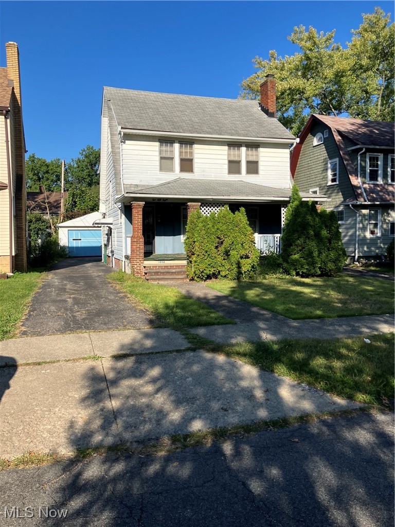 View of front of property featuring a porch, an outdoor structure, and a chimney