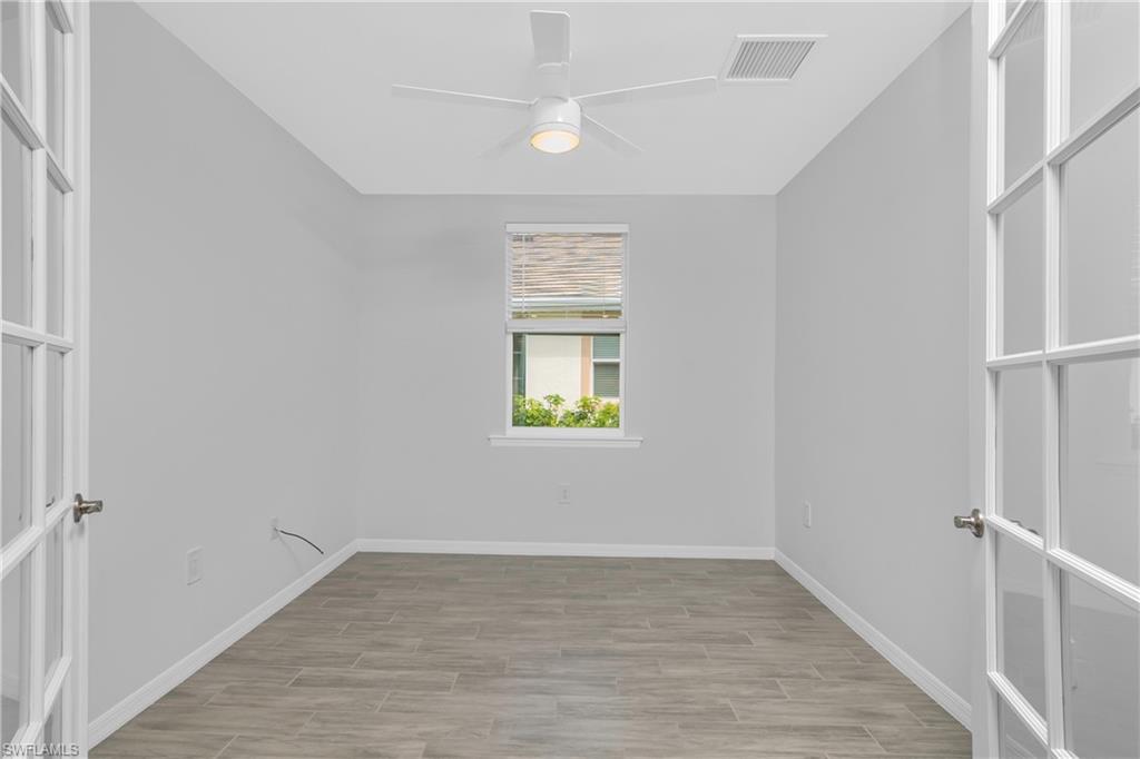 14559 Edgewater Circle Naples, FL 34114 - Photo 15 of 49 a view of an empty room with wooden floor and a window