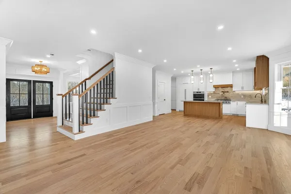 a view of a kitchen with kitchen island wooden floor and stainless steel appliances