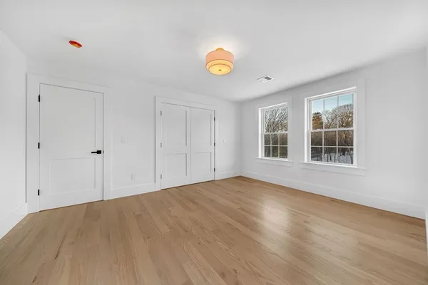 a view of an empty room with window and wooden floor