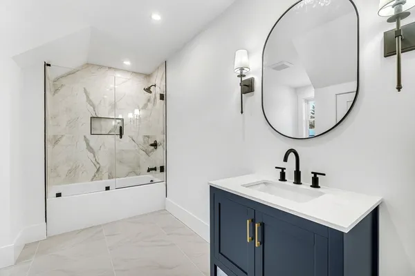 a bathroom with a sink a mirror a glass door and shower