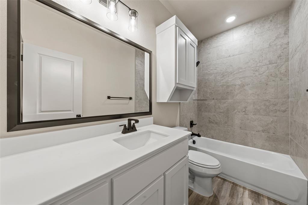 138 Dana Pt Road Lorena, TX 76655 - Photo 18 of 24 Contemporary bathroom featuring a white vanity with integrated sink, a dark framed mirror, and a combined tub and shower with light-toned tile surround