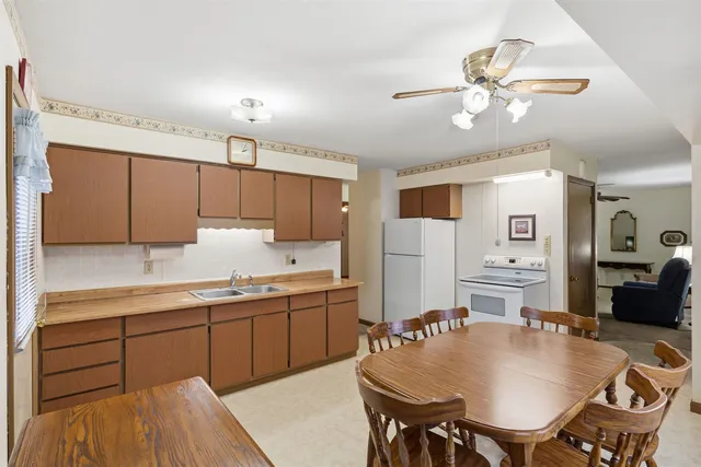 a kitchen with stainless steel appliances kitchen island granite countertop a table chairs and a refrigerator
