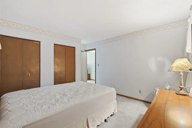 a bedroom with a bed and a lamp on dresser