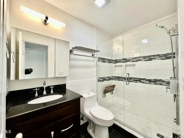 a bathroom with a granite countertop sink toilet a mirror and shower