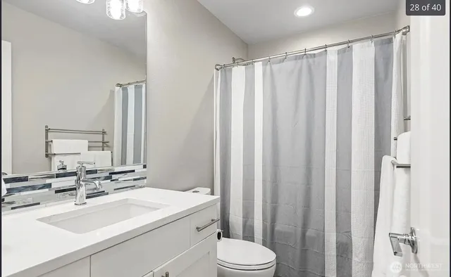 a bathroom with a sink a toilet a mirror and shower curtain