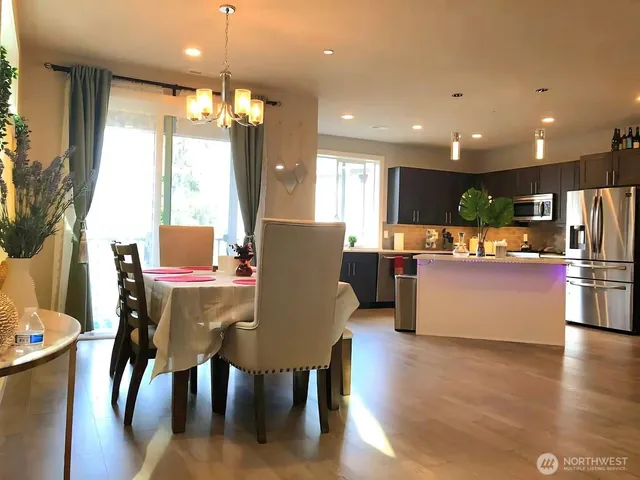 a kitchen with stainless steel appliances kitchen island granite countertop a table chairs and a refrigerator