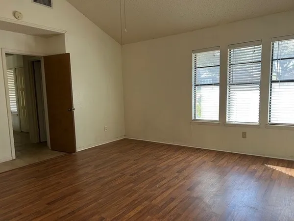 a view of an empty room with wooden floor and a window