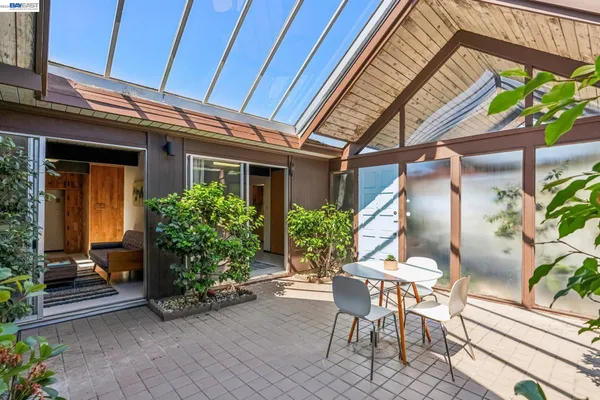a patio with table and chairs and potted plants