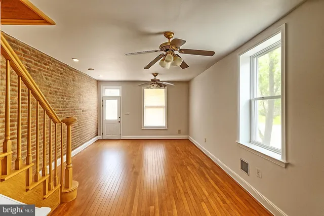 a view of empty room with wooden floor and fan