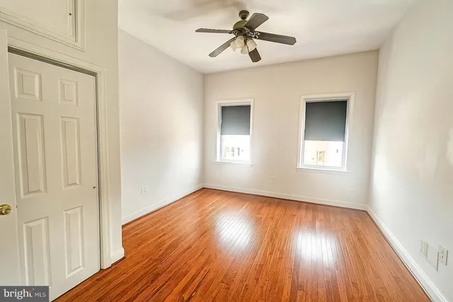 a view of empty room with wooden floor and fan