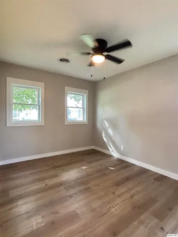 a view of an empty room with wooden floor and a window