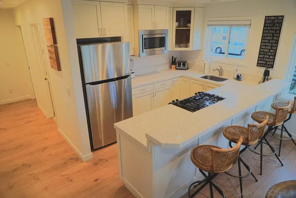 a kitchen with stainless steel appliances a refrigerator a stove a sink a dining table and chairs