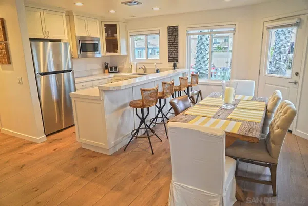 a dining room with stainless steel appliances a dining table wooden floor and window