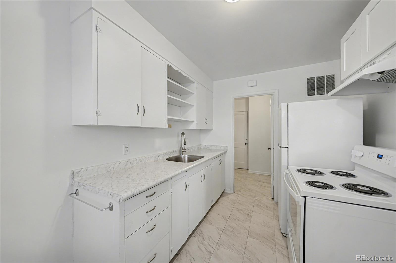 620 Strong Street, Unit 3 Brighton, CO 80601 - Photo 4 of 9 a kitchen with white cabinets and white appliances
