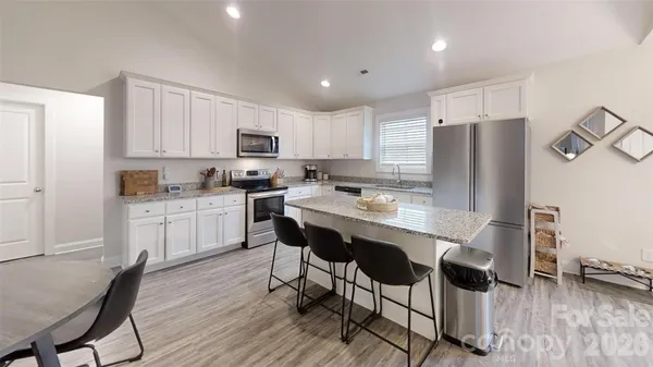 a kitchen with stainless steel appliances granite countertop a table chairs refrigerator and microwave