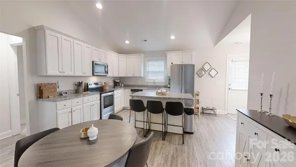 a kitchen with a dining table chairs and white cabinets