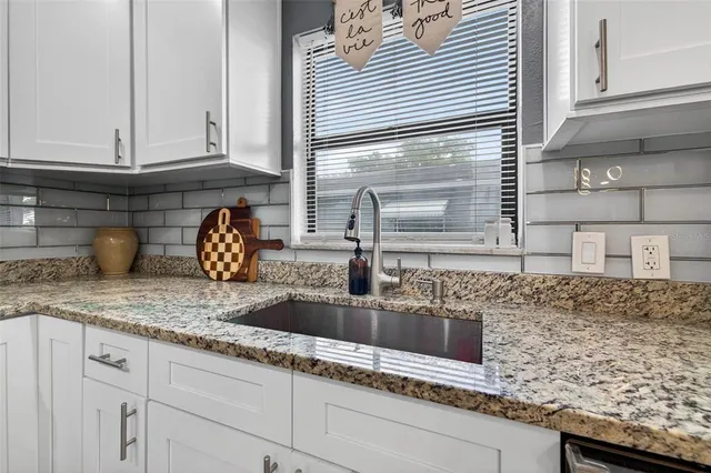 a kitchen with granite countertop a sink and cabinets