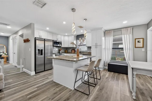 a kitchen with stainless steel appliances a refrigerator a stove a sink dishwasher with a dining table and chairs