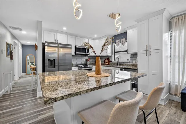 a kitchen with stainless steel appliances granite countertop a sink refrigerator and cabinets