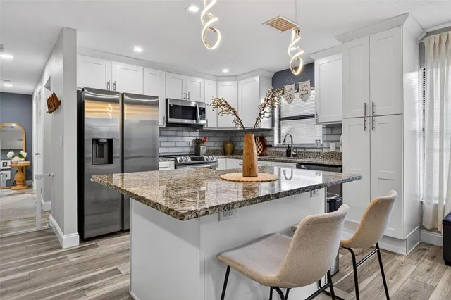a kitchen with stainless steel appliances granite countertop a sink refrigerator and cabinets