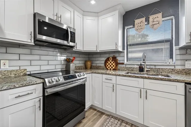 a kitchen with stainless steel appliances granite countertop a sink a stove a microwave and cabinets
