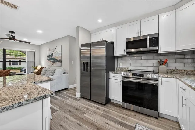 a kitchen with stainless steel appliances granite countertop a stove a refrigerator and a microwave