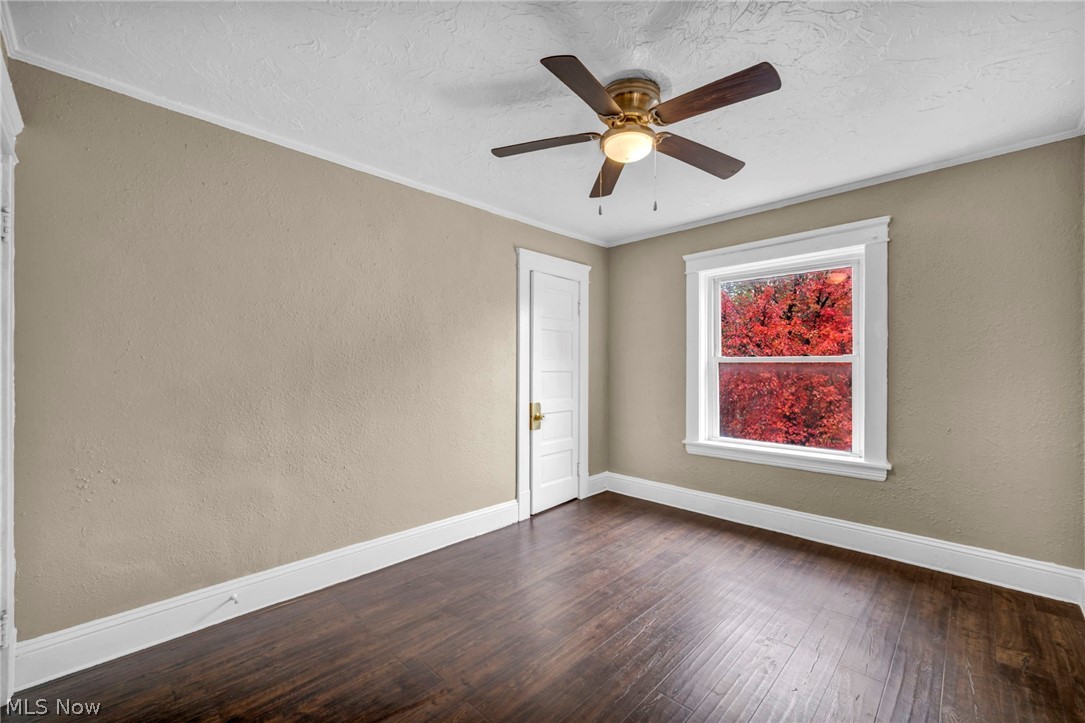 1677 Carlyon Road East Cleveland, OH 44112 - Photo 22 of 41 Spare room with a textured wall, hardwood / wood-style floors, a textured ceiling, crown molding, and a ceiling fan